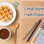 An office desk with an employee handbook, coffee, snacks and other stuff